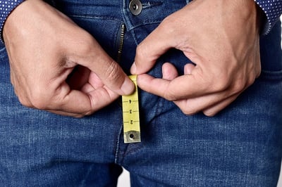 Mann mit einem Maßband, das aus seiner Jeans herausragt